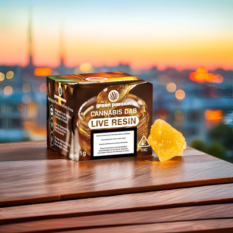 Live Resin CBD Dab 1g auf Holztisch vor verschwommener Stadtansicht bei Sonnenuntergang, zeigt Verpackung und Produktprobe.