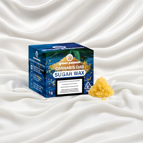Sugar Wax 1g CBD Dab auf elegantem weißen Stoff, präsentiert in einer blauen Verpackung mit goldenen Akzenten, betont die Premiumqualität.