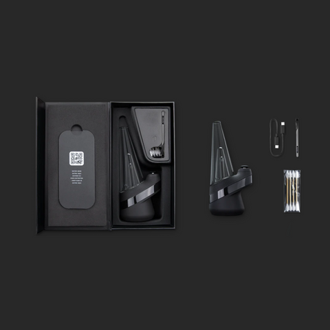 Puffco Peak Smart E-Rig Dab Vaporizer im geöffneten Karton mit Zubehör, darunter Kabel und Reinigungsstäbchen, auf dunklem Hintergrund.