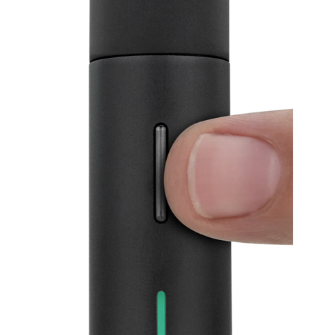Nahaufnahme eines Fingers, der den Knopf des Puffco Pivot Mini Dab Rig Vaporizers drückt, in mattem Schwarz gehalten.