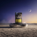 Green Passion Cannabis Product Moonrocks – 10g Packung auf Yin-Yang-Steinen in karger Mondlandschaft bei Dämmerung mit Mondsichel und Astronautenmotiv auf der Verpackung.