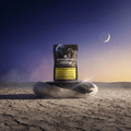 Verpackung von Green Passion Moonrocks auf einem Stein in einer Mondlandschaft mit Mond im Hintergrund.