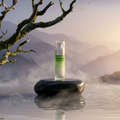 DOLOCAN Face Serum Flasche auf einem Stein in einer nebligen Landschaft mit einem Ast im Hintergrund.