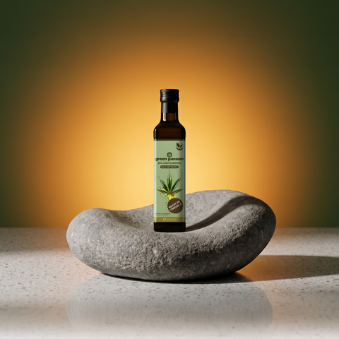 Flasche Bio-Hanfsamenöl von Green Passion auf einem Stein, mit grünem Etikett und Hanfblatt-Design, vor einem warmen, orange-grünen Hintergrund.
