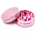 Grinder en aluminium rose à deux parties, ouvert avec des dents visibles, surface brillante, compact et stylé pour un broyage efficace.